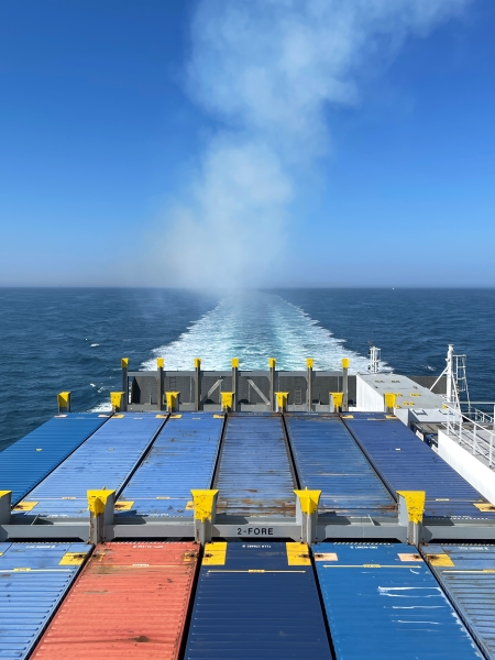 View from the deck of a GENCA cargo ship at sea, moving through the water.