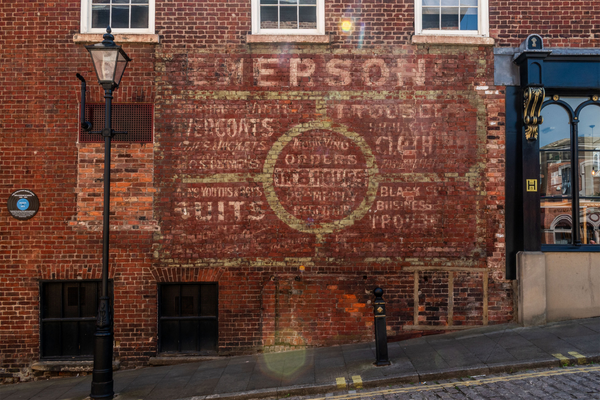 Brick wall in Stockport Old Town with remnants of old painted text.