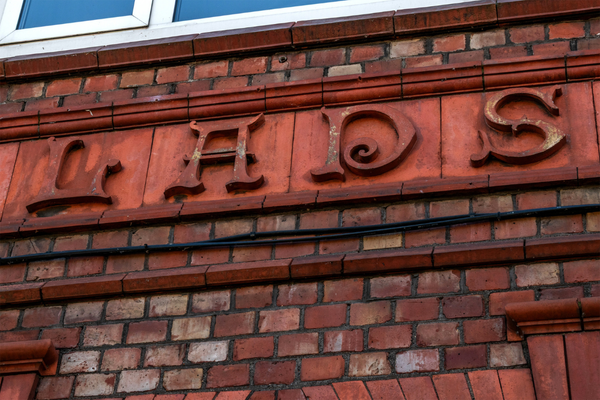 Close-up on red brick building in Stockport. Letters "LADS" are carved in relief. 