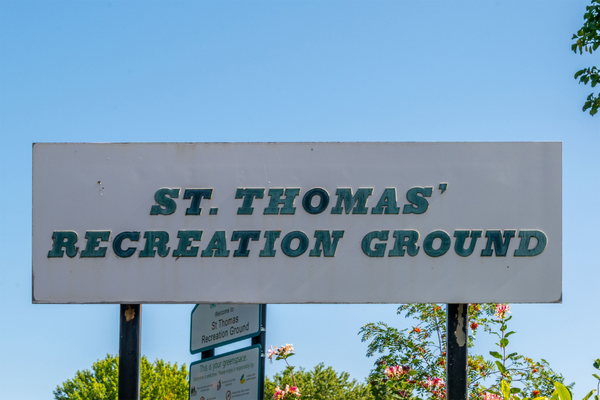 Billboard sign in Stockport, UK. White background with green faded all caps letters: "ST. THOMAS' RECREATION GROUND"