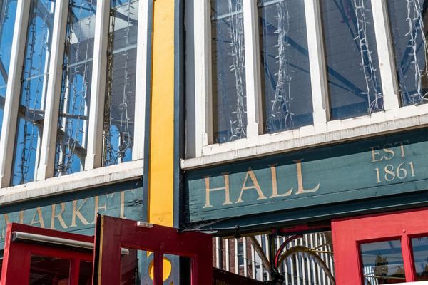 Outside Market Hall in Stockport, UK. Green background with gold painted letters: "MARKET HALL" and smaller: "EST 1861"