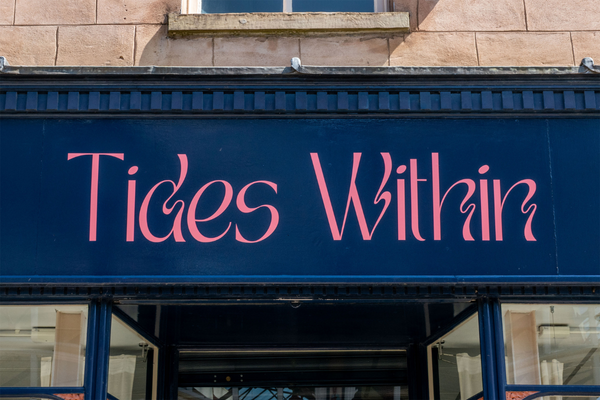 Stockport Old Town storefont. Pink letters painted on a dark deep blue background. Text: "Tides Within"