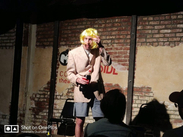 Bill Connolly performing on stage in costume and a blond wig.