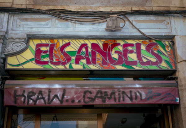 Stained glass sign in Barcelona with graffiti below it.