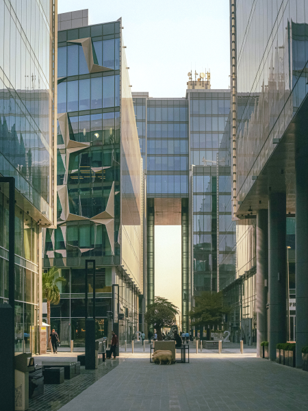 Towering structures at Dubai Design District. Buildings are covered in windows, reflecting the other buildings surrounding the walkway.