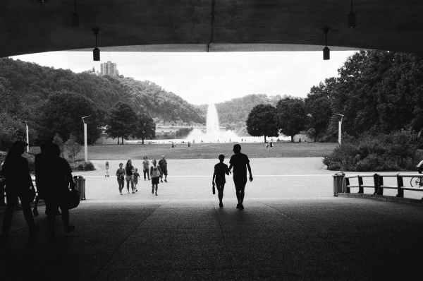 Black and white photo of people walking together in a vibrant park scene. Photo by Jake Murtaugh.
