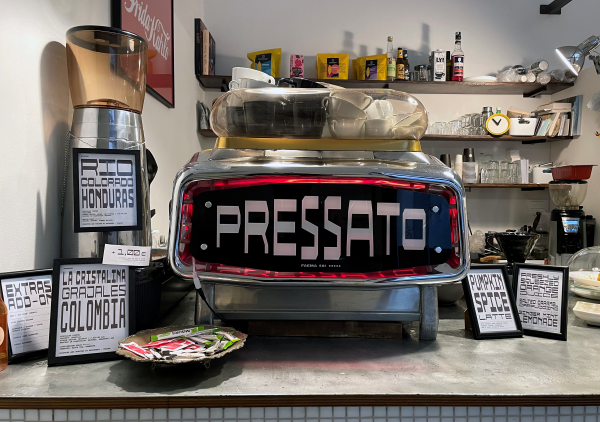 Resistenza’s Pressato typeface pictured in white letters on a black background with a red border on an espresso machine at Pressato Coffee & Books in Torino, Italy. Photo by Nello Russo.