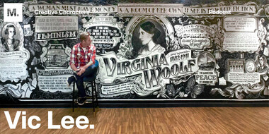 Photo of artist Vic Lee sitting in front of a typographic mural celebrating the life of Virginia Woolf