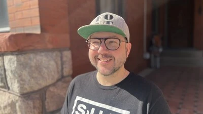 Portrait of Phil Carey-Bergren standing outside in the sun.