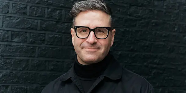 Portrait of Charles Nix wearing a black shirt in front of a black brick background cropped 16x9. Portrait of Charles Nix wearing a black shirt in front of a black brick background cropped 16x9.