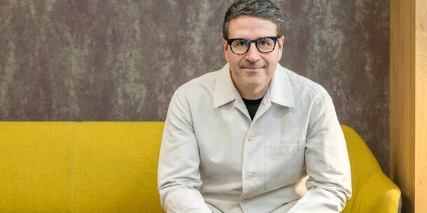 Charles Nix sitting for a portrait on a yellow couch.