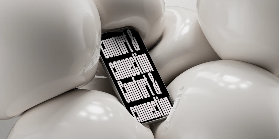 A phone pictured squished between several white balls. Black background with white text: "comfort & connection Comfort & connection"